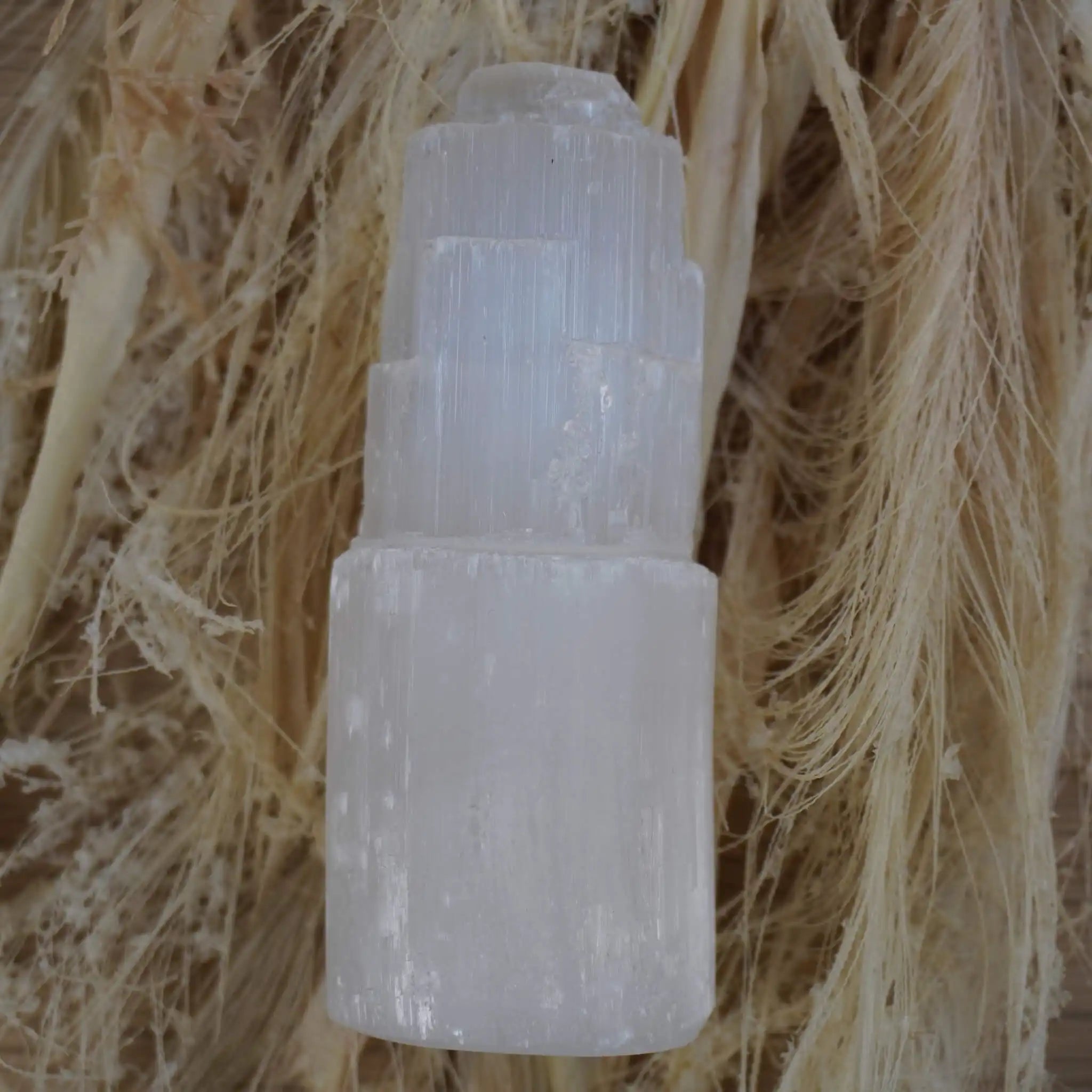 Selenit Turm Kristall auf hellem Hintergrund mit Naturfasern