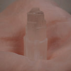 Selenit Turm Kristall vor rosa Stoffhintergrund