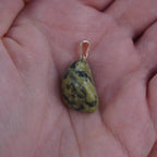 Serpentin Trommelstein Kettenanhänger mit silberner Öse in einer Hand liegend