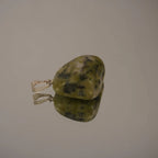 Grün gemusterter Serpentin Trommelstein Kettenanhänger mit Silber Öse auf glänzender Fläche