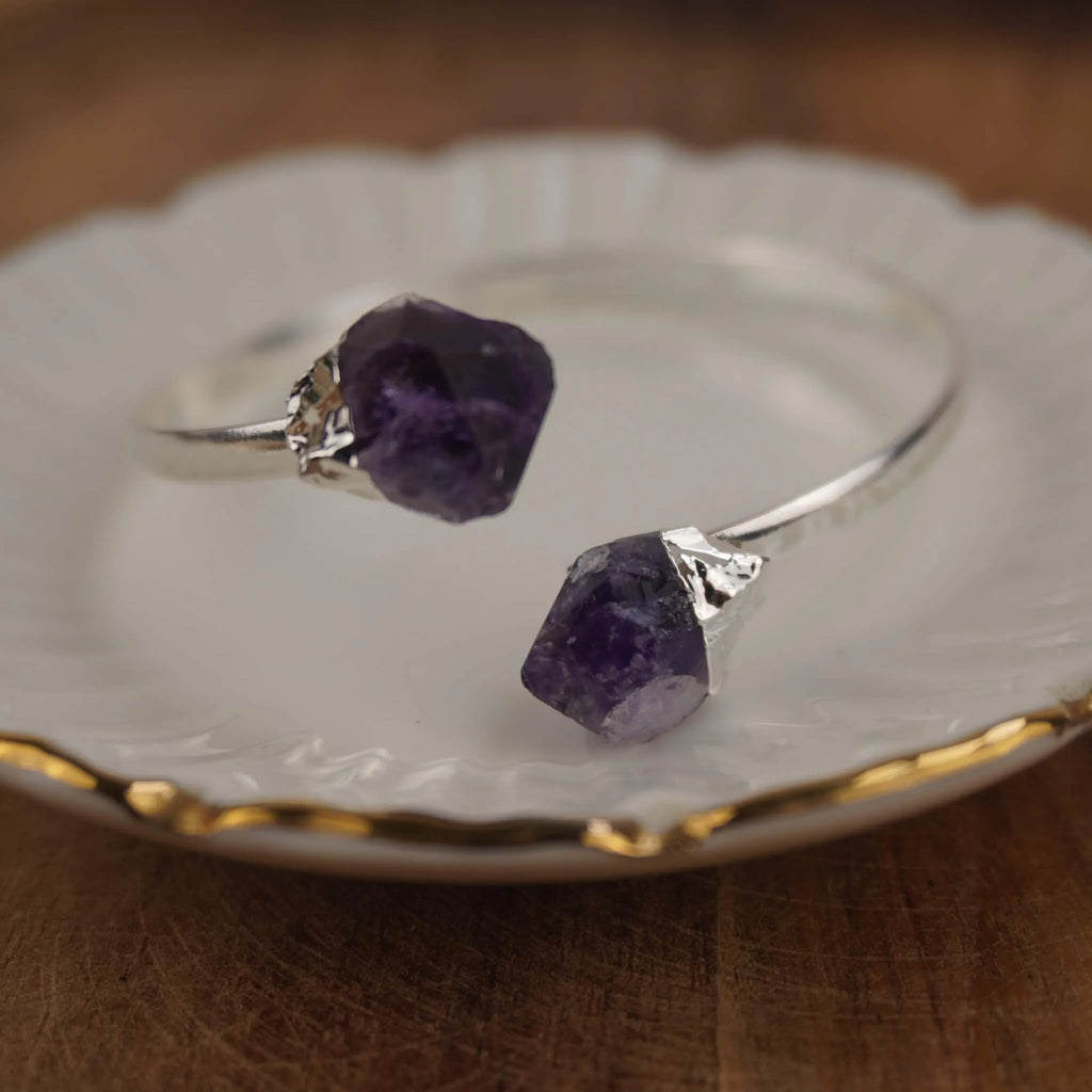 Silberarmreif mit zwei Roh Amethysten dekoriert auf weißem Schmuckteller