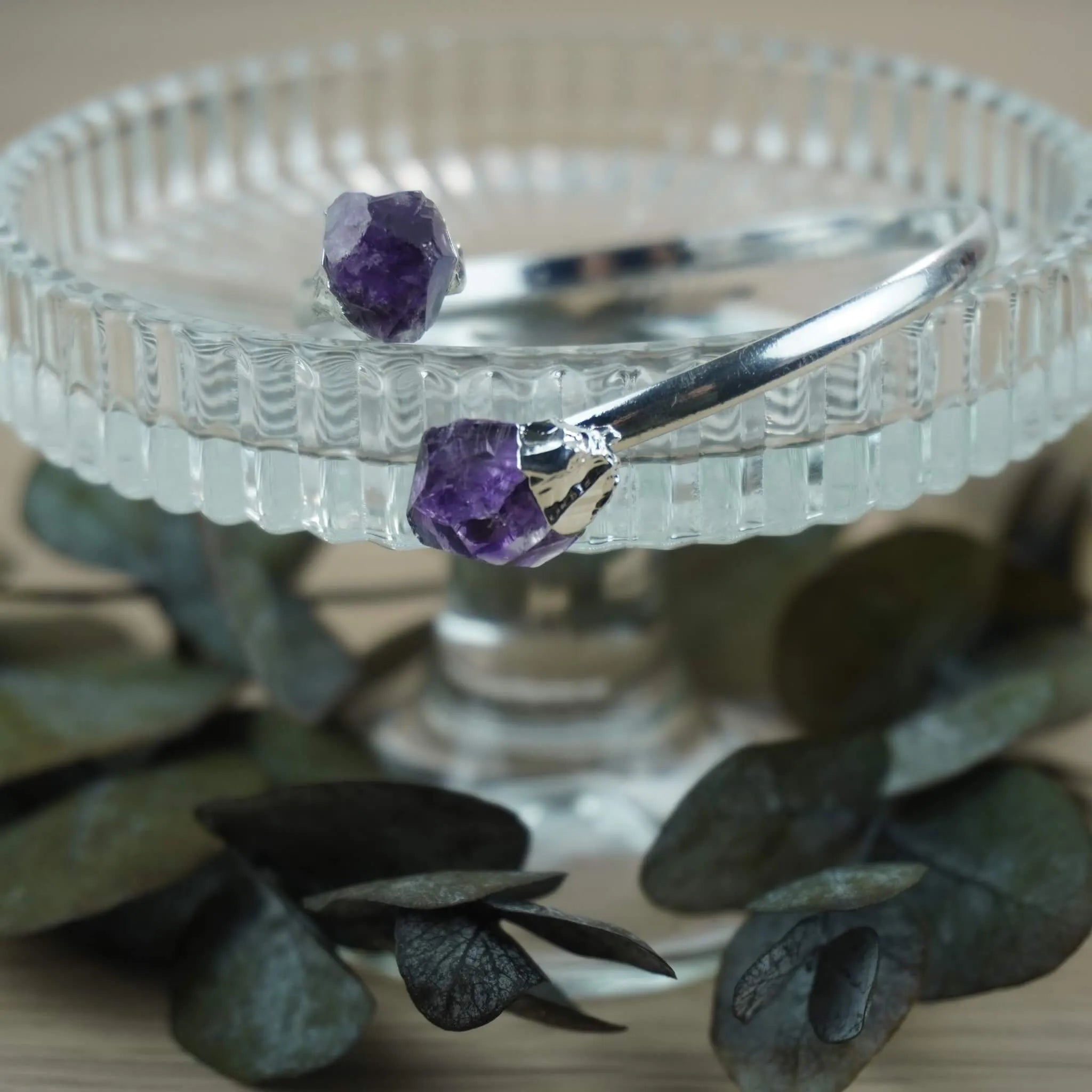 Silberarmreif mit zwei Roh Amethysten auf Glasständer mit Eukalyptus dekoriert