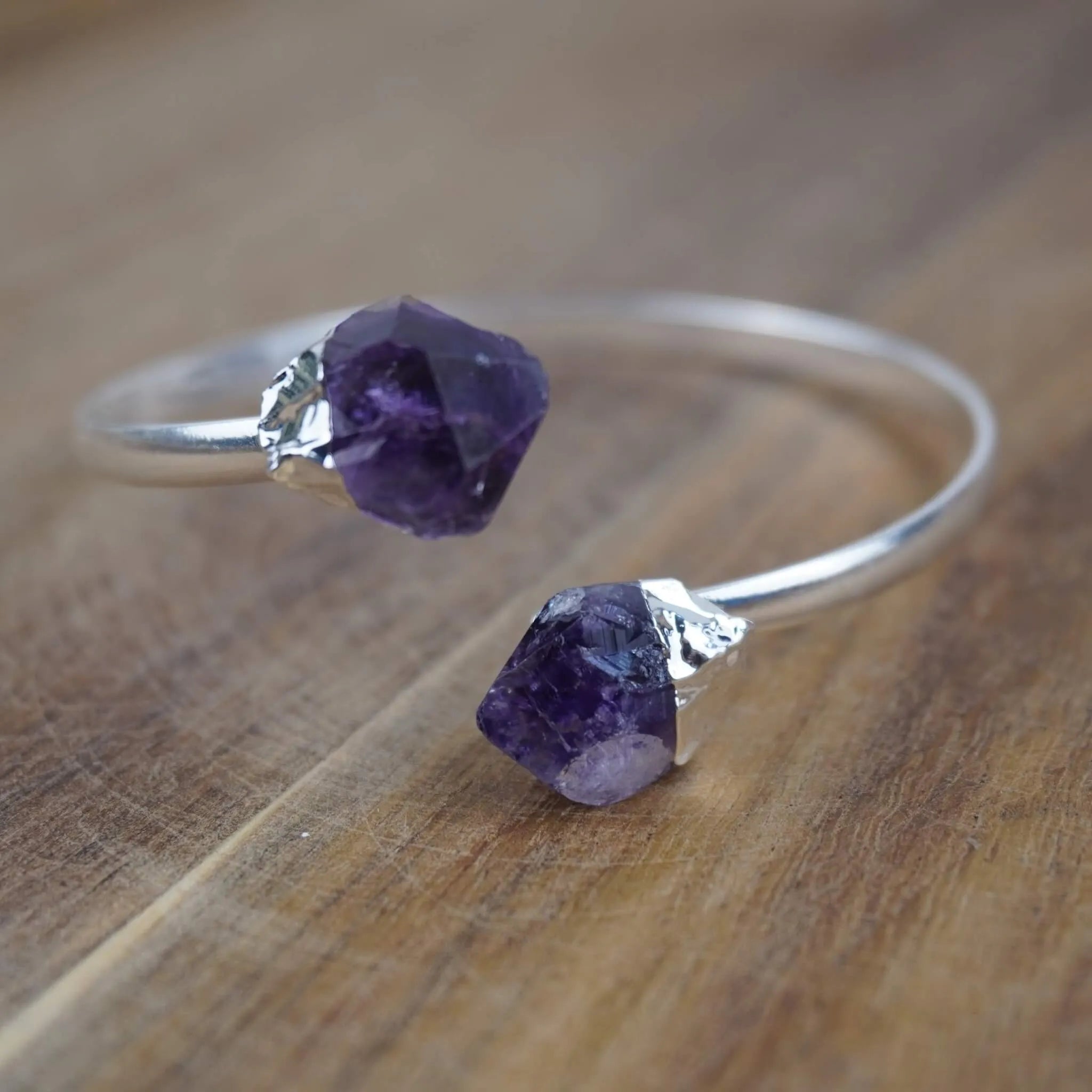 Silberarmreif mit zwei Roh Amethysten auf rustikaler Holzoberfläche