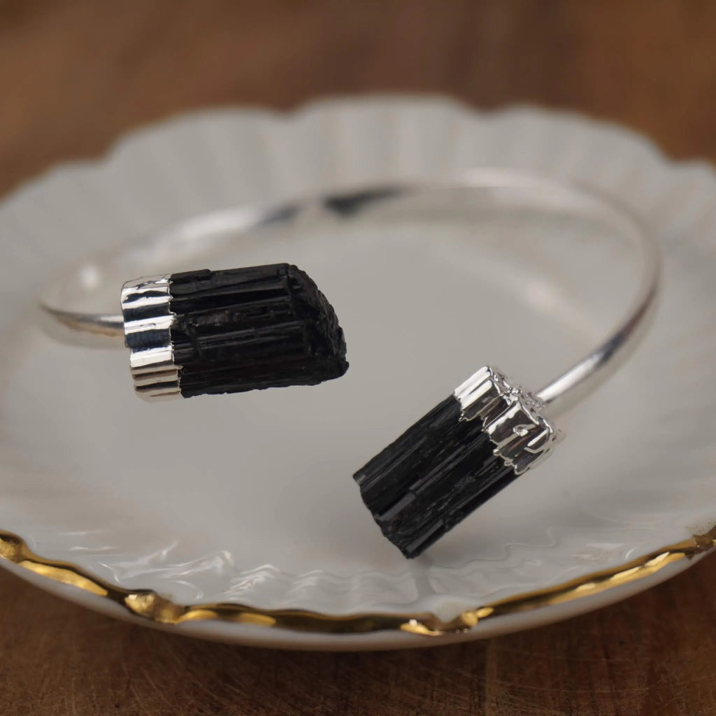 Silberarmreif mit zwei rohen schwarzen Turmalinen auf weißem Porzellanteller