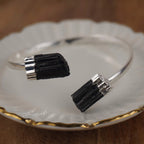 Silberarmreif mit zwei rohen schwarzen Turmalinen auf weißem Porzellanteller