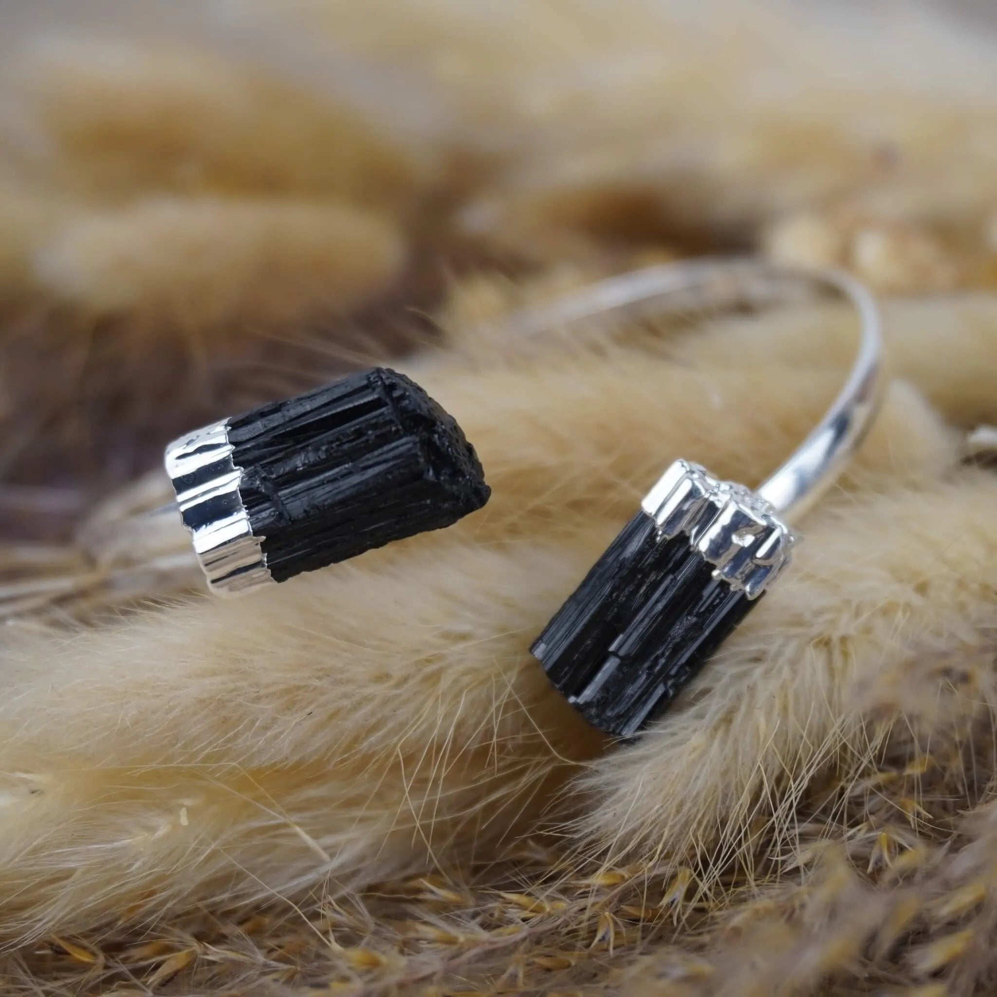 Silberarmreif mit rohen schwarzen Turmalinen auf flauschigen Trockenpflanzen