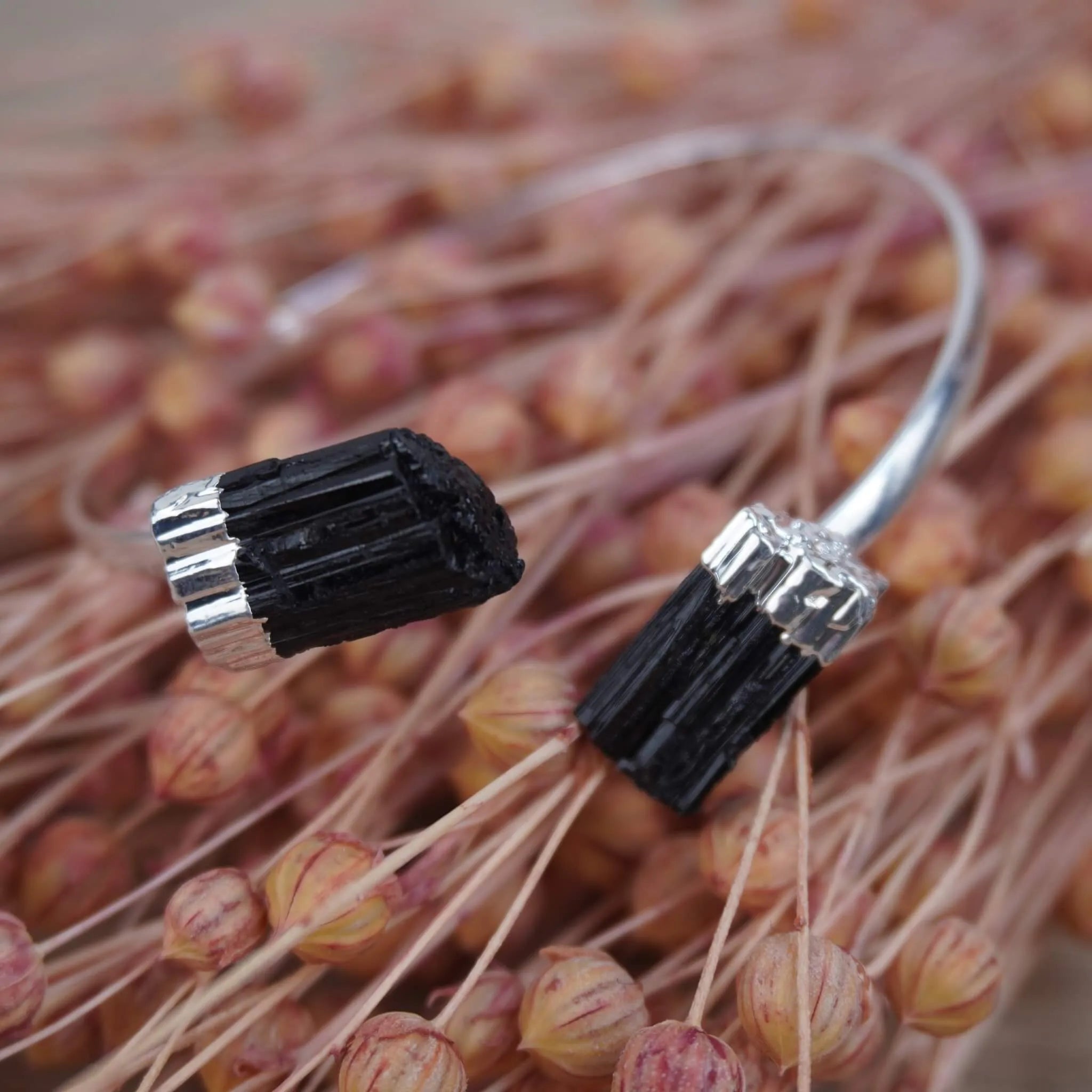 Silberarmreif mit zwei rohen schwarzen Turmalinen dekoriert auf getrockneten Gräsern