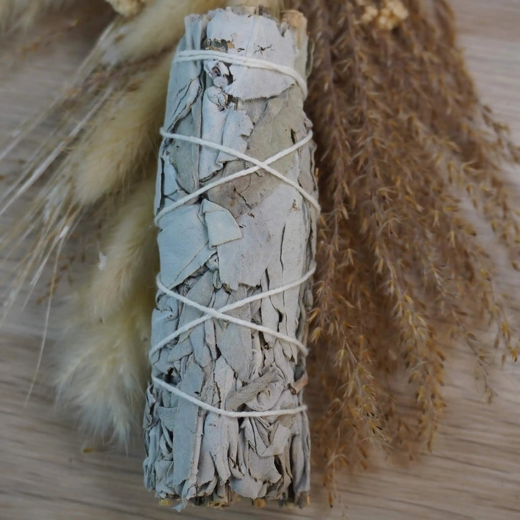 Smudge Stick aus weißem Salbei dekoriert mit getrockneten Gräsern