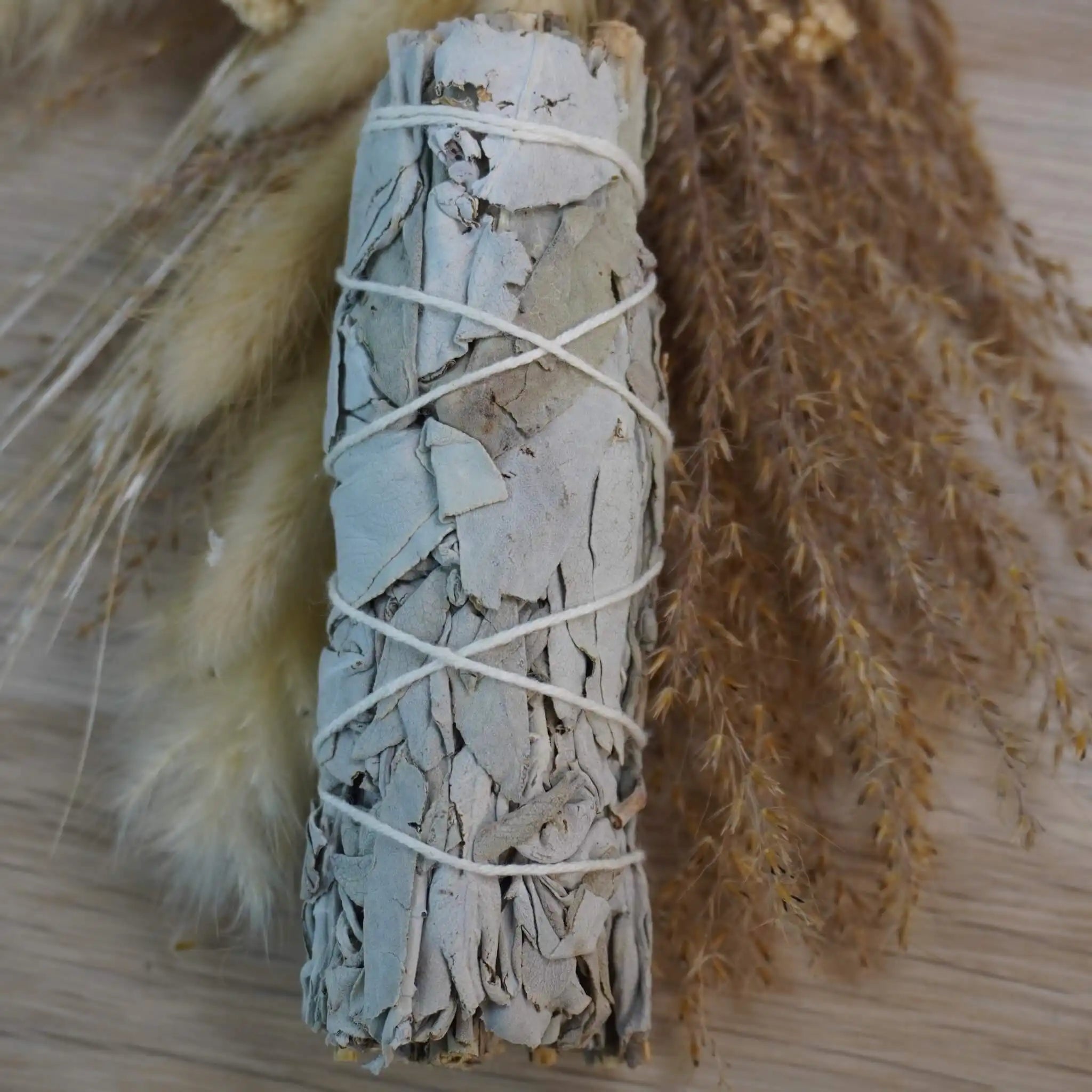 Smudge Stick aus weißem Salbei dekoriert mit getrockneten Gräsern