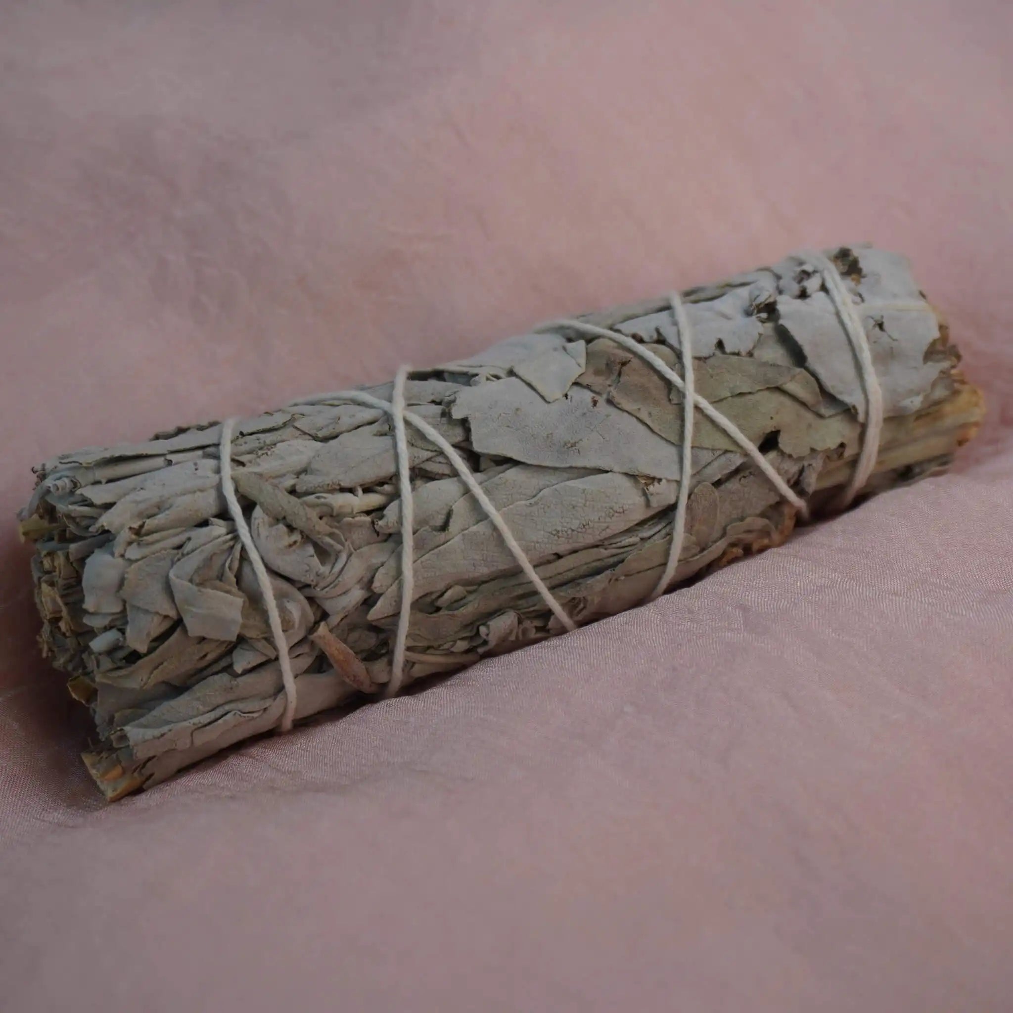 Smudge Stick aus weißem Salbei auf rosa Stoffuntergrund