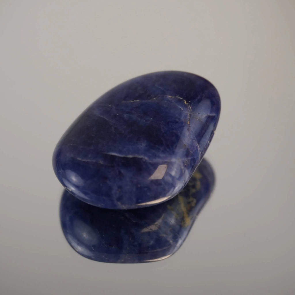 Sodalith Trommelstein als glatter Einzelstein auf heller Fläche