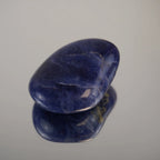 Sodalith Trommelstein als glatter Einzelstein auf heller Fläche