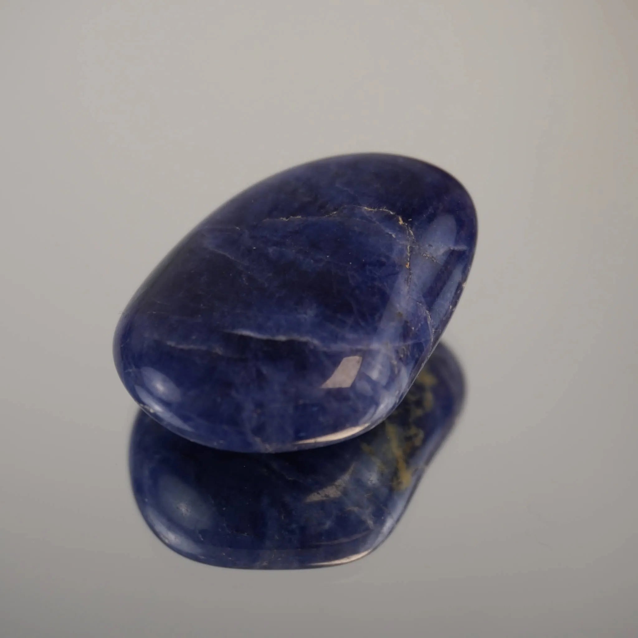 Sodalith Trommelstein als glatter Einzelstein auf heller Fläche