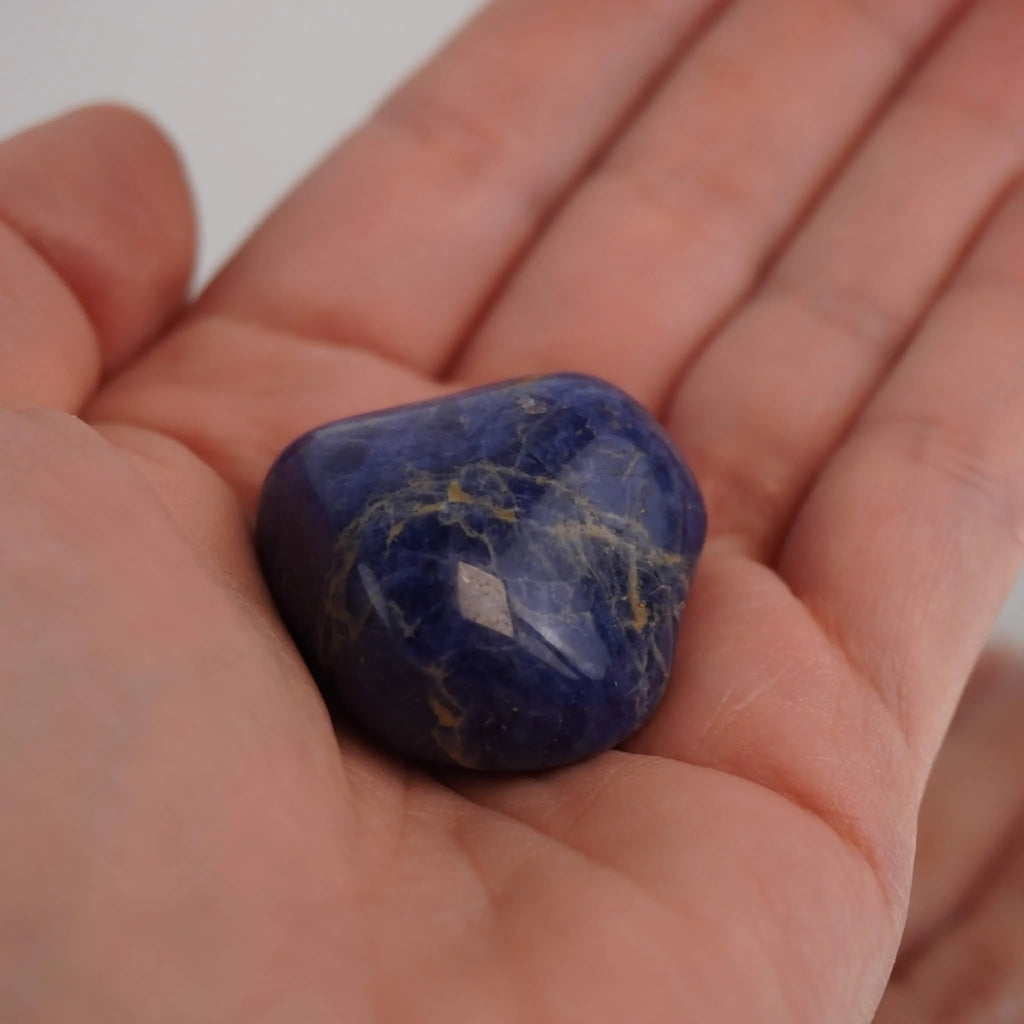 Sodalith Trommelstein liegend in einer Hand