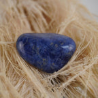 Sodalith Trommelstein auf hellem Naturfaserdekor natürlich präsentiert