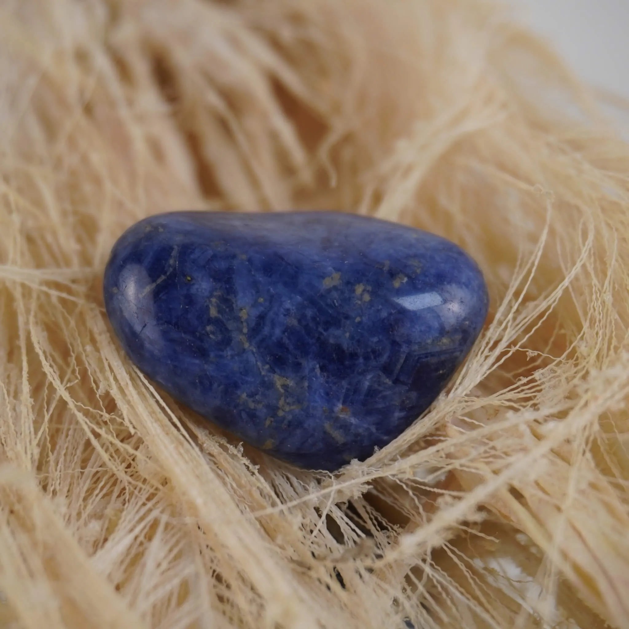 Sodalith Trommelstein auf hellem Naturfaserdekor natürlich präsentiert