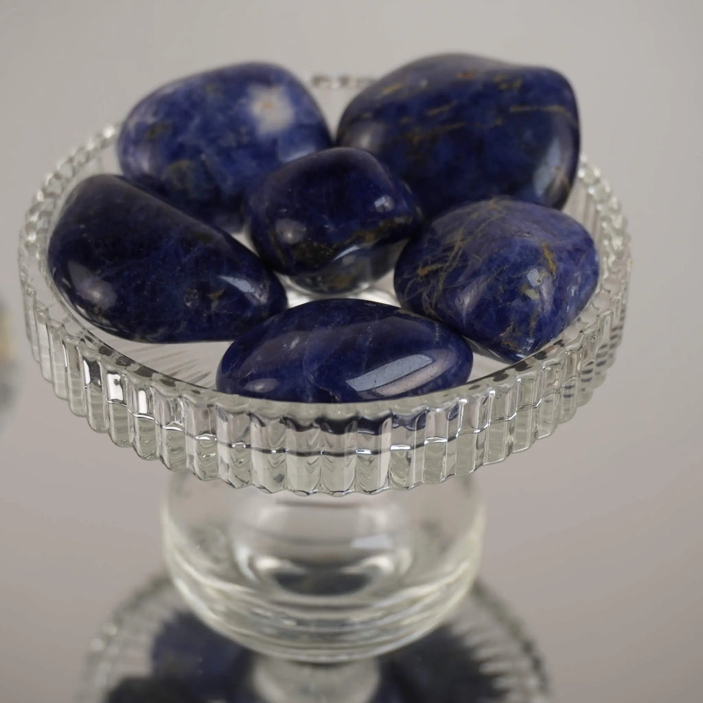 Mehrere Sodalith Trommelsteine in klarer Glasschale auf spiegelnder Fläche