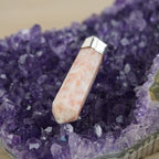 Sonnenstein Spitze Kettenanhänger mit silberfarbener Fassung präsentiert auf violetter Amethyst-Druse