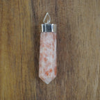 Sonnenstein Spitze Kettenanhänger mit silberfarbener Fassung vor Holzuntergrund