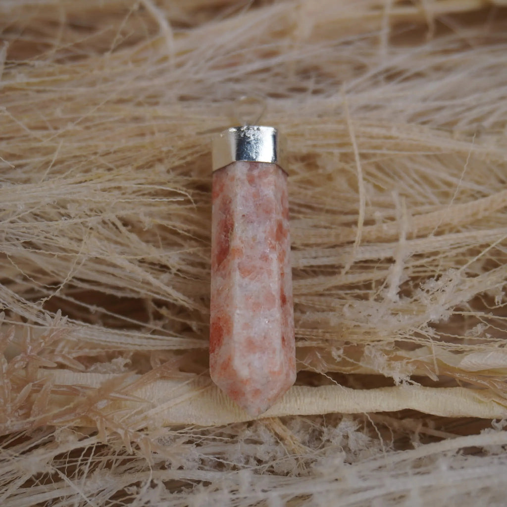 Sonnenstein Spitze Kettenanhänger mit silberfarbener Fassung auf hellen Naturfasern