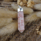 Sonnenstein Spitze Kettenanhänger mit silberfarbener Fassung auf beigen Trockenpflanzen