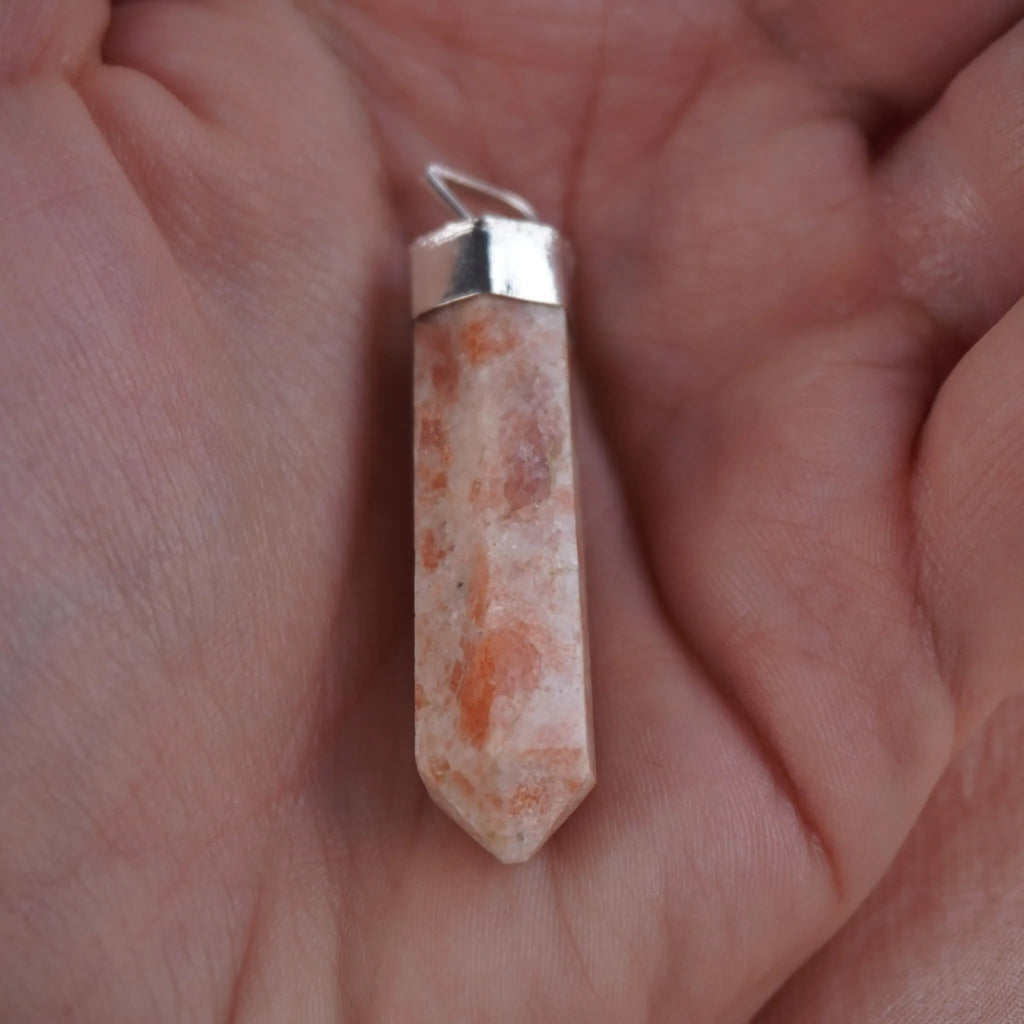 Sonnenstein Spitze Kettenanhänger mit silberfarbener Fassung in einer Hand liegend