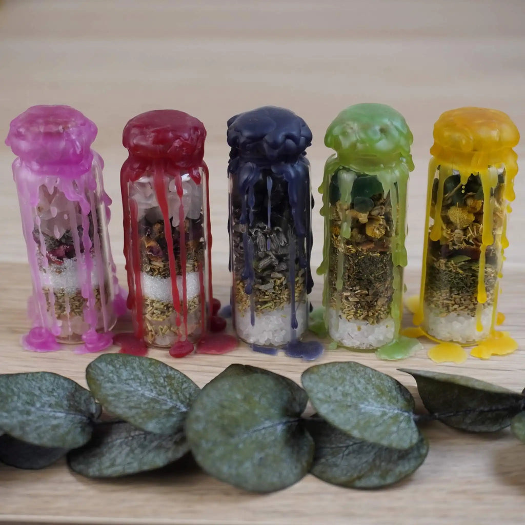 Spell Jar Set aus fünf handgefertigten Gläsern mit buntem Wachs in lila, rot, blau, grün und gelb, gefüllt mit Kristallen und Kräutern