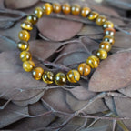 Tigerauge Kugelarmband auf braunen Blättern