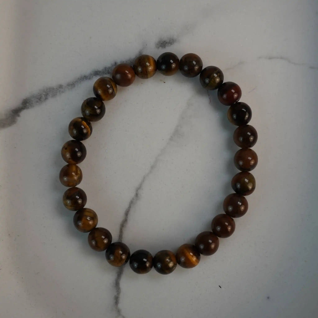 Tigerauge Kugelarmband aus polierten Perlen auf weißem Marmor-Hintergrund