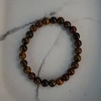 Tigerauge Kugelarmband aus polierten Perlen auf weißem Marmor-Hintergrund