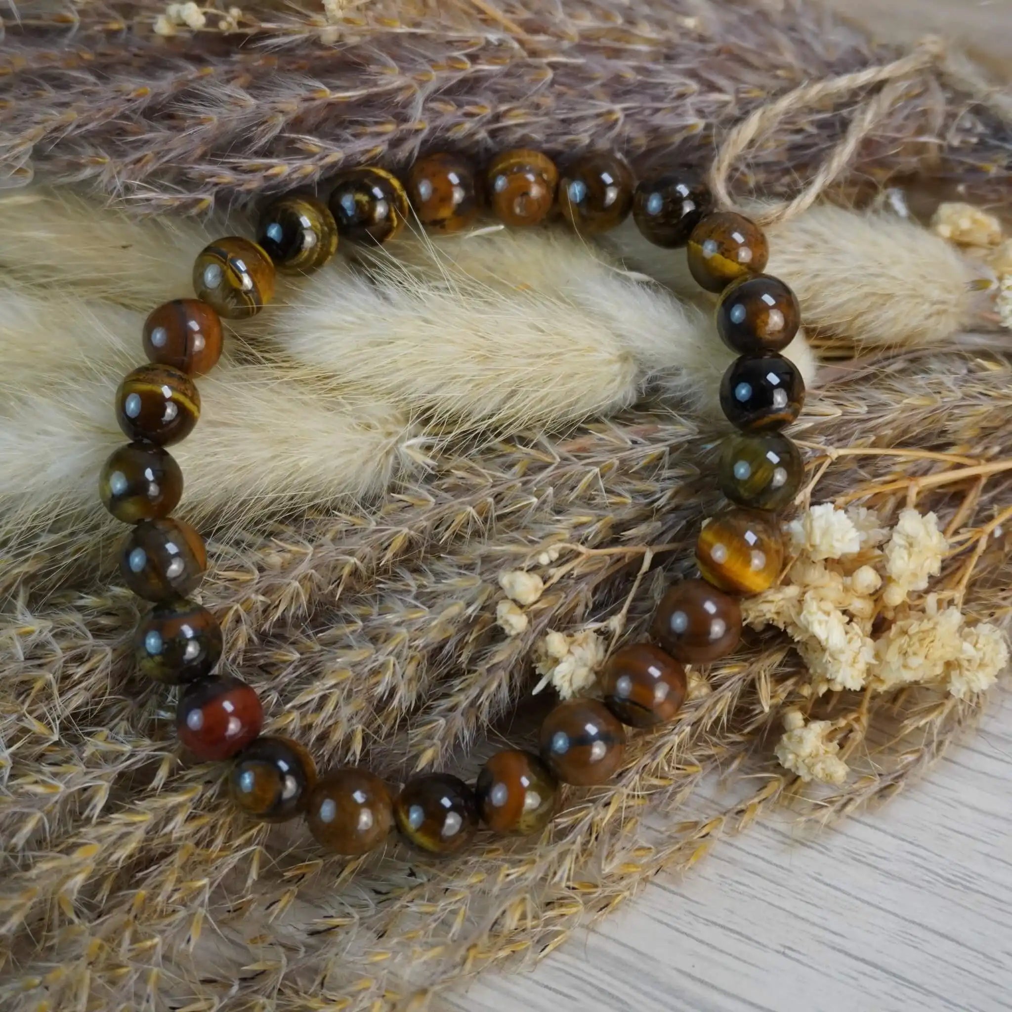 Tigerauge Kugelarmband arrangiert auf Trockenblumen und Gräsern