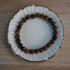 Tigerauge Kugelarmband auf weißer Porzellanschale mit Goldrand