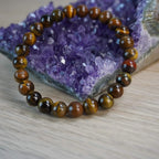 Tigerauge Kugelarmband dekoriert vor einem Amethyststein