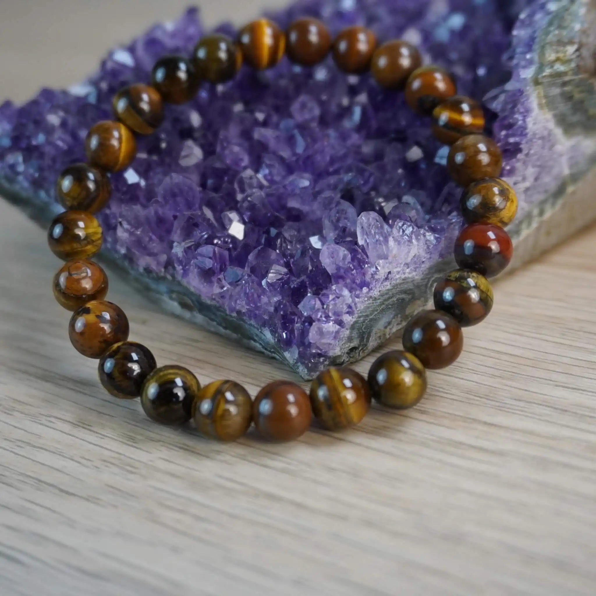 Tigerauge Kugelarmband dekoriert vor einem Amethyststein