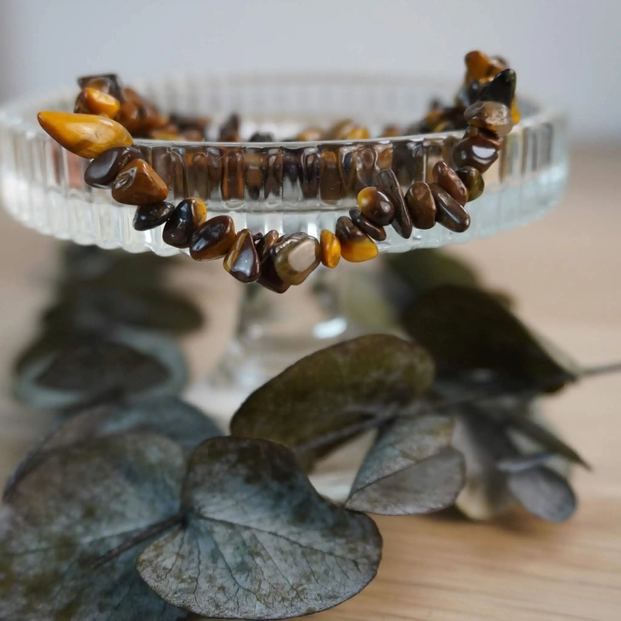 Tigerauge Splitterarmband auf Glasständer mit Blättern