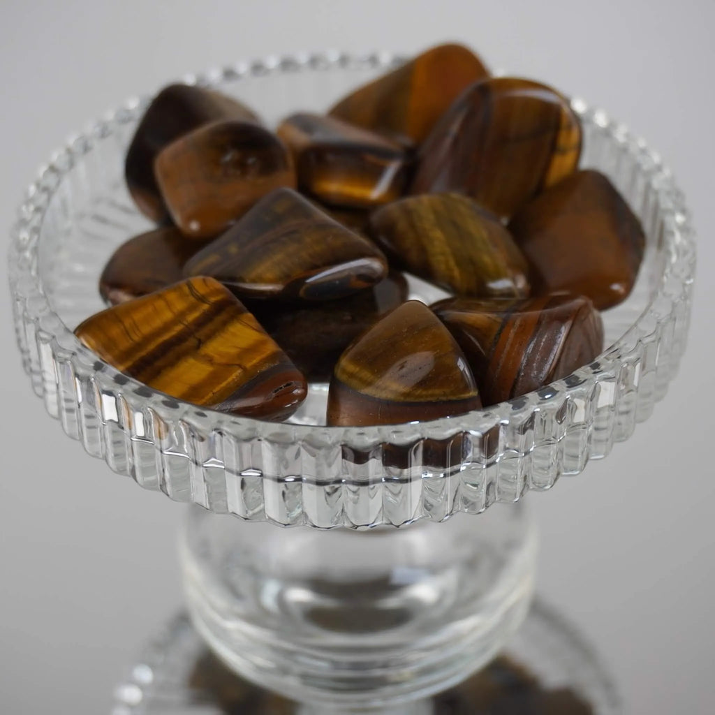 Mehrere Tigerauge Trommelsteine in gläserner Schale dekorativ präsentiert