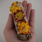 Weißer Salbei Räucherbündel mit Siempreviva Blüten wird in einer Hand gehalten