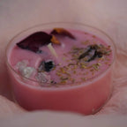 Rosa Maxi-Teelicht mit Zimtduft und Mondstein, dekoriert mit Blüten und Kräutern auf zarter Stoffunterlage